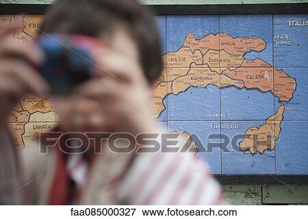 Stock Photo - Map of Italy painted on wall, young tourist in foreground. Fotosearch