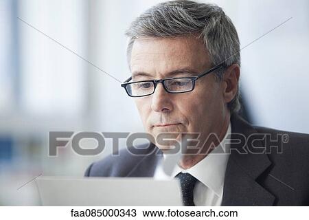 Stock Image - Mature businessman reading document. Fotosearch