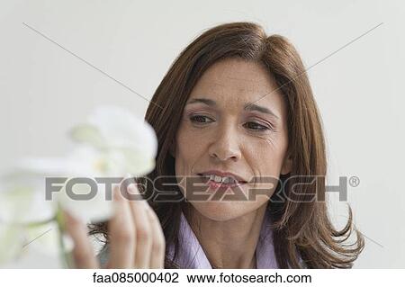 Stock Image - Mature businesswoman looking at flowers. Fotosearch