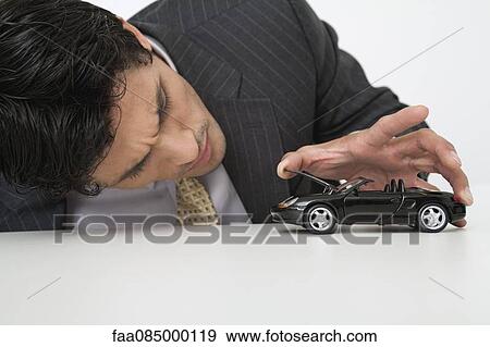 Mid-adult businessman looking at toy car View Large Photo Image Stock Photo - Mid-adult businessman looking at toy car. Fotosearch