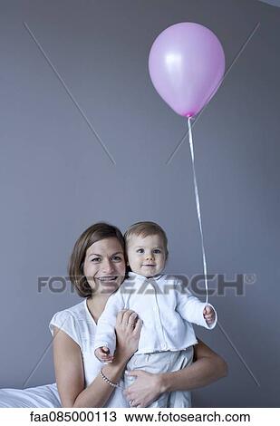 Stock Image - Mother and baby, baby holding balloon. Fotosearch