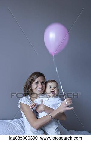 Stock Image - Mother and baby playing with balloon. Fotosearch