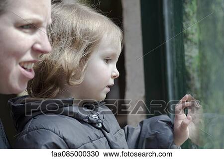 Mother and young daughter looking through window together View Large Photo Image Stock Image - Mother and young daughter looking through window together. Fotosearch