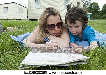 Mother and young son lying on blanket, working puzzles in newspaper together View Large Photo Image Stock Photography - Mother and young son lying on blanket, working puzzles in newspaper together. Fotosearch