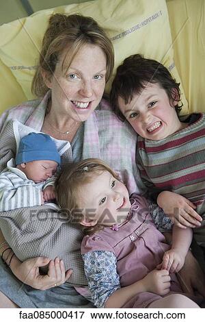Stock Photo - Mother sitting on hospital bed with children and newborn baby, portrait. Fotosearch