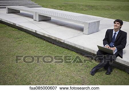 Stock Photo - Young businessman using laptop computer outdoors. Fotosearch