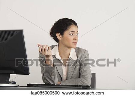 Stock Image - Young businesswoman holding yin g balls at desk. Fotosearch