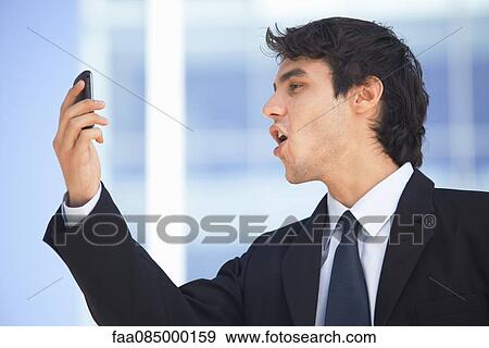 Young executive video calling on cell phone outdoors View Large Photo Image Stock Photo - Young executive video calling on cell phone outdoors. Fotosearch