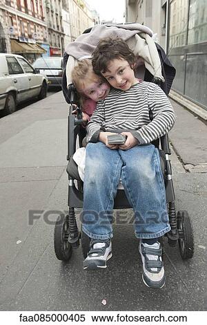Stock Photography - Young siblings sitting together in stroller. Fotosearch