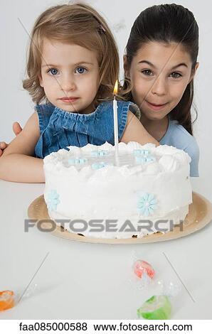 Stock Photo - Young sisters with birthday cake. Fotosearch