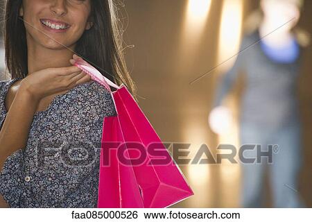 Stock Photograph - Young woman carrying shopping bags, cropped. Fotosearch
