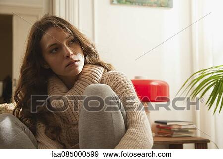 Young woman hugging knee, looking away in thought View Large Photo Image Stock Photo - Young woman hugging knee, looking away in thought. Fotosearch