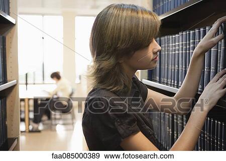 Young woman looking at books in library View Large Photo Image Stock Photo - Young woman looking at books in library. Fotosearch