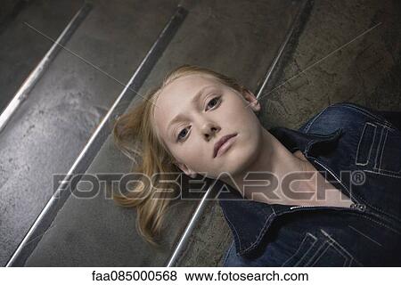 Stock Photo - Young woman lying on stairs, portrait. Fotosearch