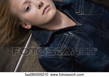 Stock Image - Young woman lying on the ground, portrait. Fotosearch