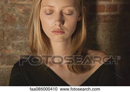 Stock Image - Young woman with eyes closed, portrait. Fotosearch