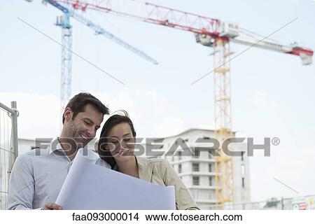 Architects reviewing blueprint in construction site View Large Photo Image Picture - Architects reviewing blueprint in construction site. Fotosearch