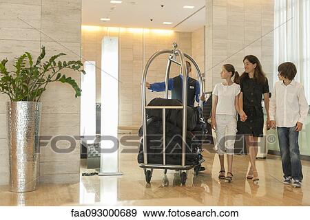 Bellhop assising mother and children with luggage in hotel lobby View Large Photo Image Stock Photo - Bellhop assising mother and children with luggage in hotel lobby. Fotosearch