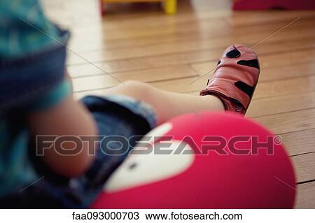 Stock Image - Boy sitting on cushion, low section. Fotosearch