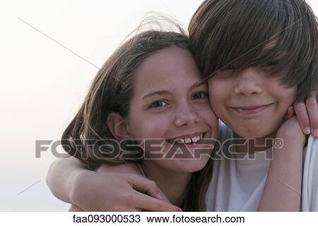 Stock Image - Brother and sister embracing, portrait. Fotosearch