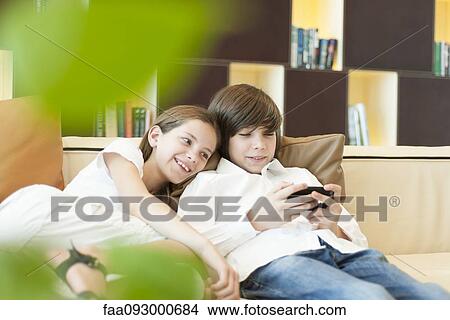 Picture - Brother and sister looking at cell phone together. Fotosearch