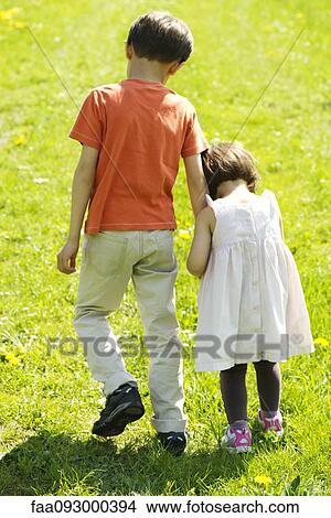 Brother and sister walking hand-in-hand through field View Large Photo Image Picture - Brother and sister walking hand-in-hand through field. Fotosearch