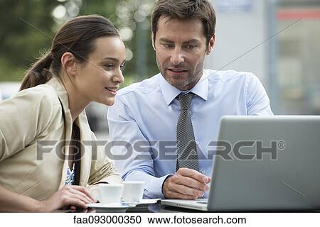 Stock Image - Business associates working together using laptop computer outdoors. Fotosearch