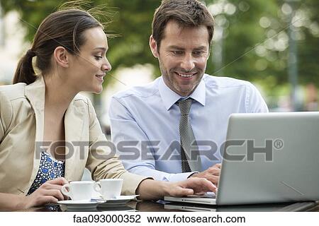 Stock Image - Business associates working together using laptop computer outdoors. Fotosearch