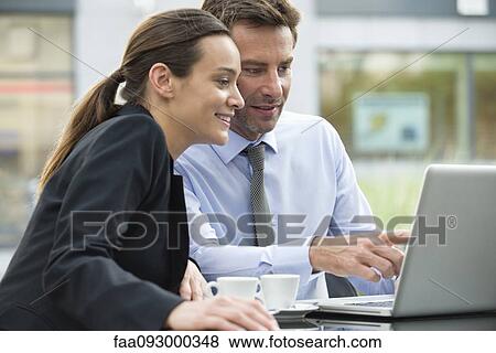 Business associates working together using laptop computer outdoors View Large Photo Image Stock Photo - Business associates working together using laptop computer outdoors. Fotosearch