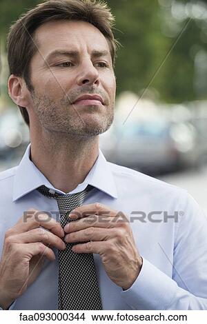 Businessman putting on necktie View Large Photo Image Picture - Businessman putting on necktie. Fotosearch
