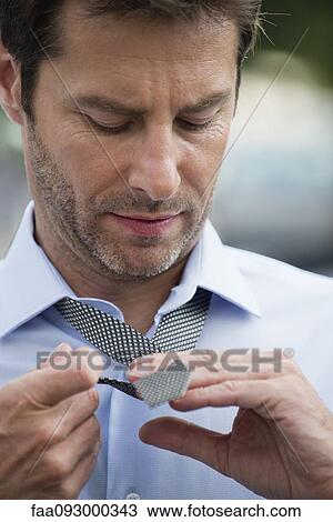 Businessman putting on necktie View Large Photo Image Stock Image - Businessman putting on necktie. Fotosearch