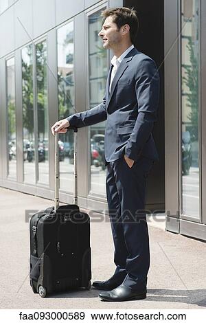 Businessman standing and waiting with luggage View Large Photo Image Stock Photo - Businessman standing and waiting with luggage. Fotosearch
