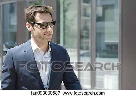 Businessman with sunglasses walking in city View Large Photo Image Stock Photo - Businessman with sunglasses walking in city. Fotosearch