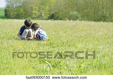 Stock Image - Children picking wildflowers in meadow. Fotosearch