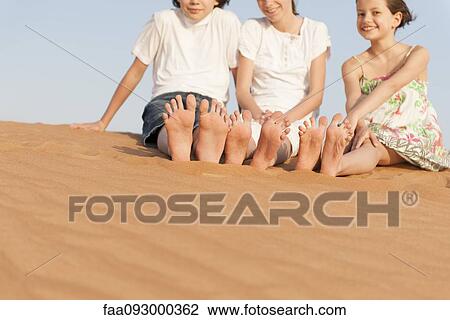 Stock Image - Children sitting on sand dune. Fotosearch