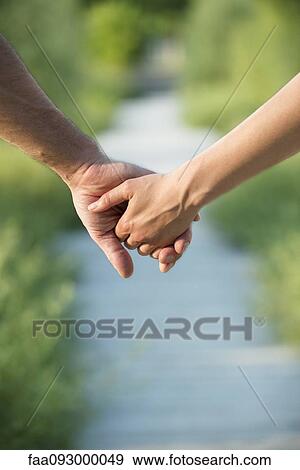 Stock Photo - Couple holding hands, close-up. Fotosearch