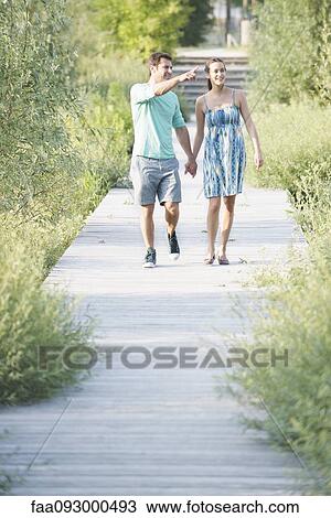 Couple holding hands enjoying walk along boardwalk through nature preserve View Large Photo Image Stock Image - Couple holding hands enjoying walk along boardwalk through nature preserve. Fotosearch