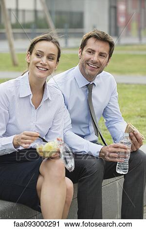 Stock Image - Coworkers having lunch together outdoors. Fotosearch