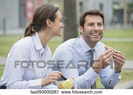 Stock Photo - Coworkers having lunch together outdoors. Fotosearch