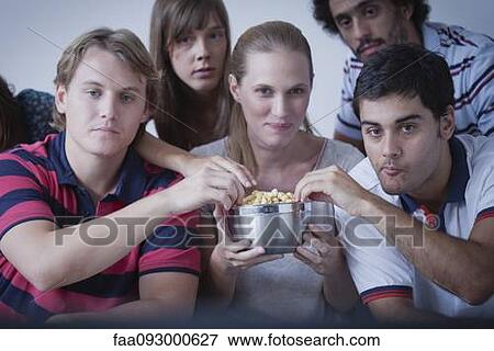 Stock Photo - Friends sharing popcorn and watching movie together. Fotosearch
