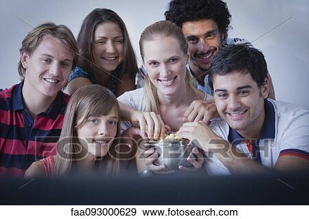 Stock Photo - Friends sharing popcorn and watching movie together. Fotosearch