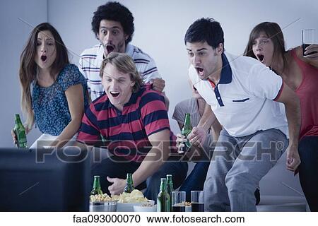 Stock Image - Friends watching exciting sports match on television together. Fotosearch