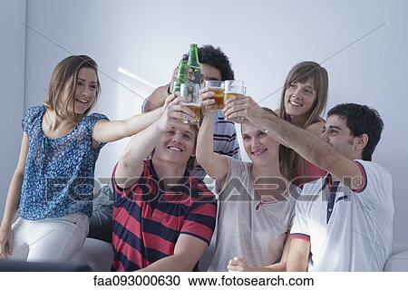 Stock Image - Friends watching sports match on television together celebrate team's victory. Fotosearch