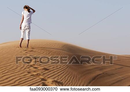 Stock Image - Girl ascending sand dune. Fotosearch