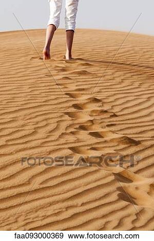 Stock Photo - Girl ascending sand dune. Fotosearch