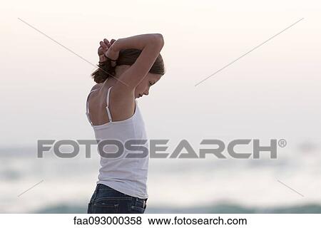 Girl putting hair in ponytail, side view View Large Photo Image Stock Photo - Girl putting hair in ponytail, side view. Fotosearch