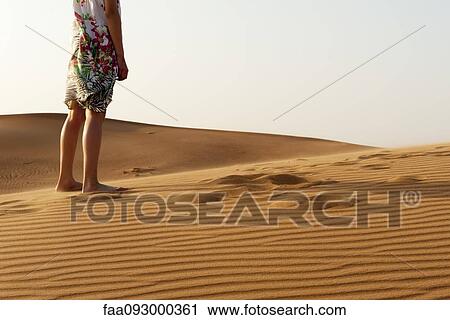 Stock Image - Girl standing barefoot in desert, cropped. Fotosearch