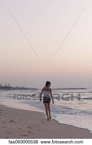 Stock Photo - Girl walking on beach, looking at sea. Fotosearch