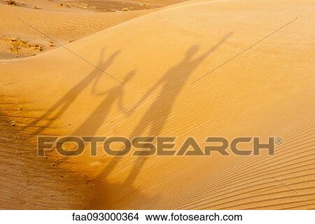 Holding hands together, shadow cast on desert sand View Large Photo Image Picture - Holding hands together, shadow cast on desert sand. Fotosearch