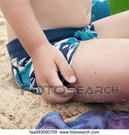 Little boy sitting on sand, scratching leg, cropped View Large Photo Image Stock Photo - Little boy sitting on sand, scratching leg, cropped. Fotosearch